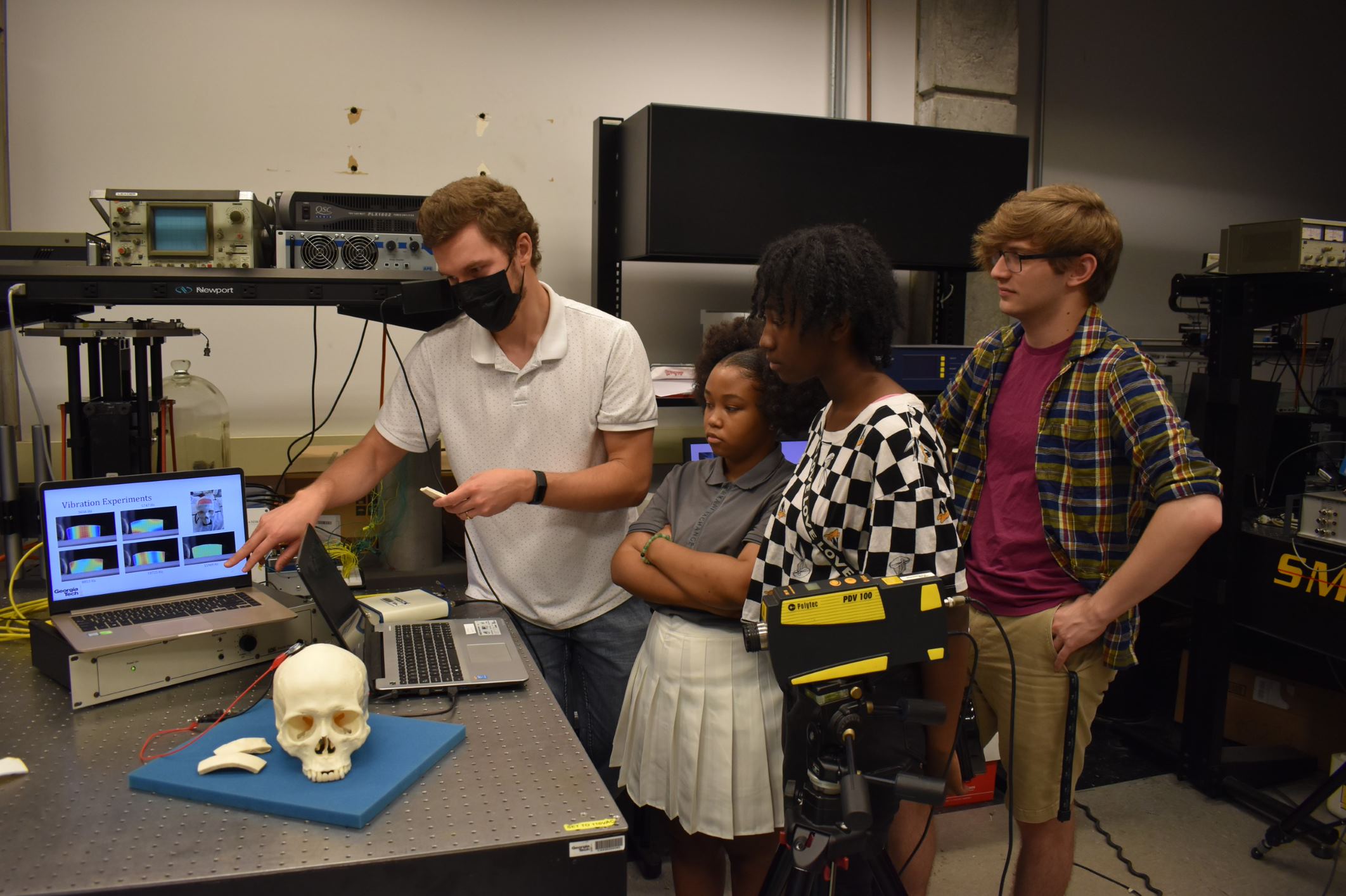 Students and a pre-teaching intern gather around a computer for an experiment
